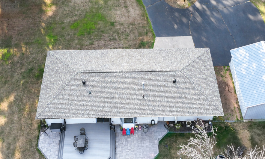 Aerial view of a hip roof above a covered patio with new grey shingles