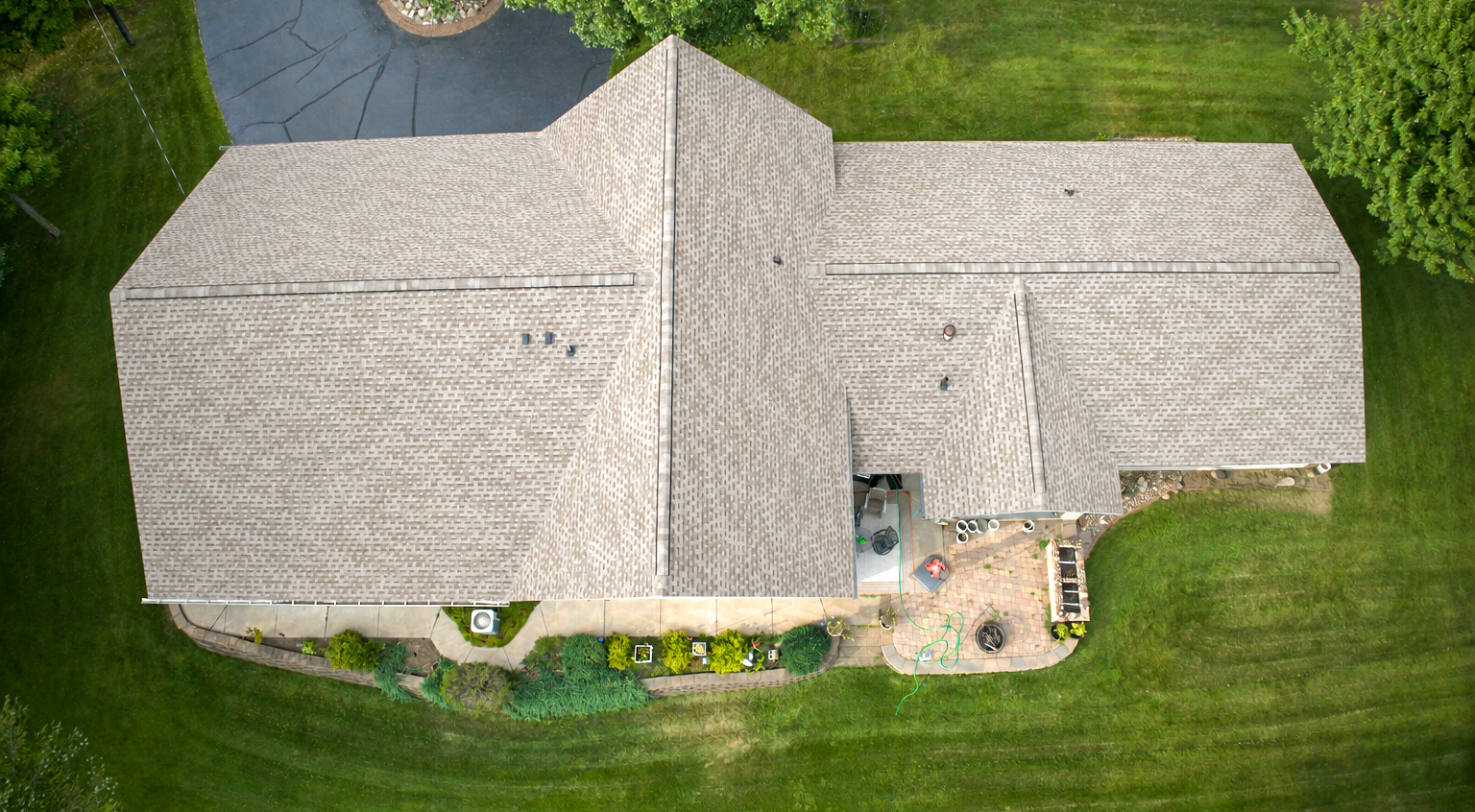 Overhead aerial view of a lake home with multiple architectural shingle roof planes