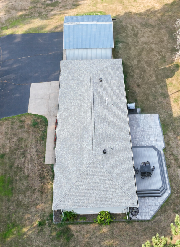 Aerial view of a long ranch home with light grey architectural shingles and continuous ridge ventilation
