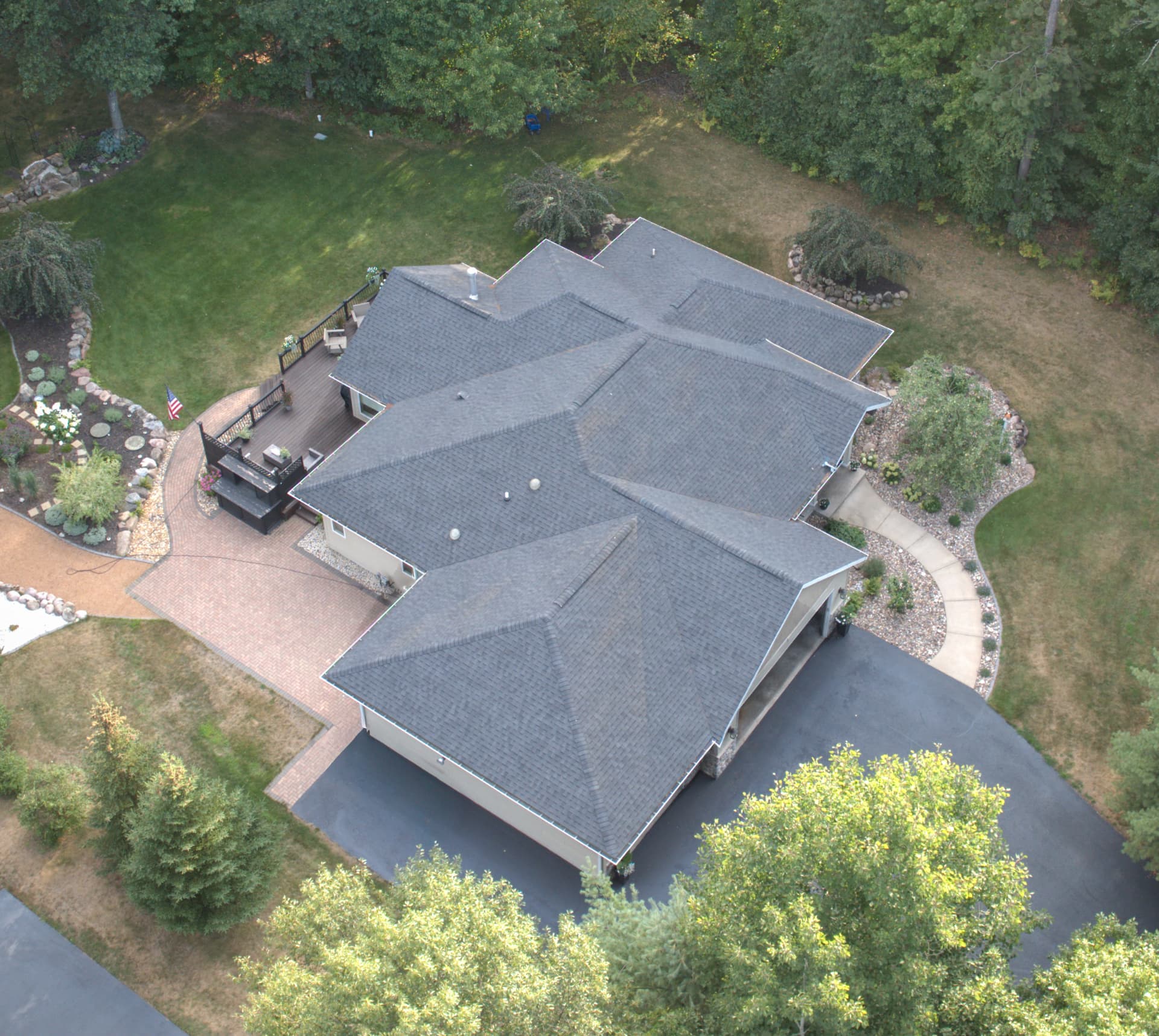Aerial view of a shingled roof with attached garage and clean eave lines