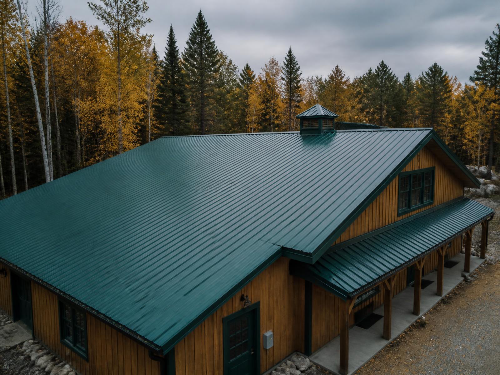 Forest green exposed-fastener ribbed ag panel metal roof on a Wisconsin pole shed and detached garage